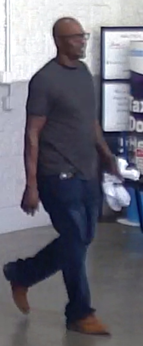 Photo of suspect at Wal-Mart. Suspect is wearing black framed glasses, dark colored shirt with jeans and brown shoes.
